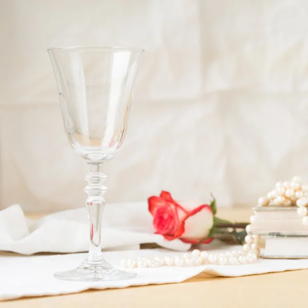 Beautiful empty glass with vintage books and pearls