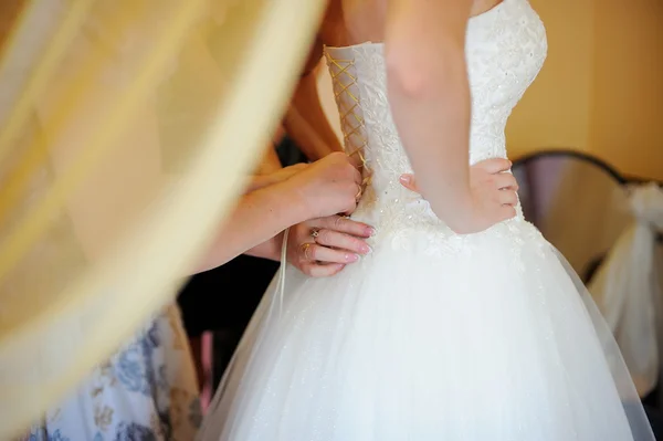 Bridesmaid is helping the bride to dress