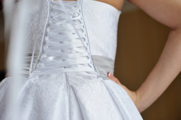 Bridesmaid is helping the bride to dress