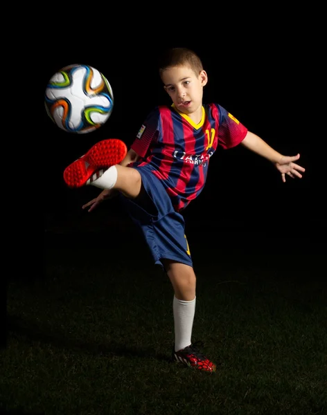 Low key portrait of a boy kicking a world cup football