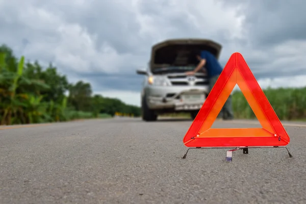 Triangle Red emergency stop sign, with repair broken, damaged cars parked on the street