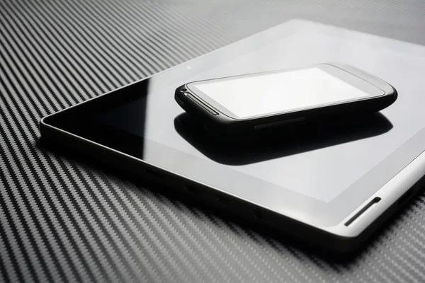 Blank Smartphone With Reflection Lying On Business Tablet With Reflection On Carbon Background
