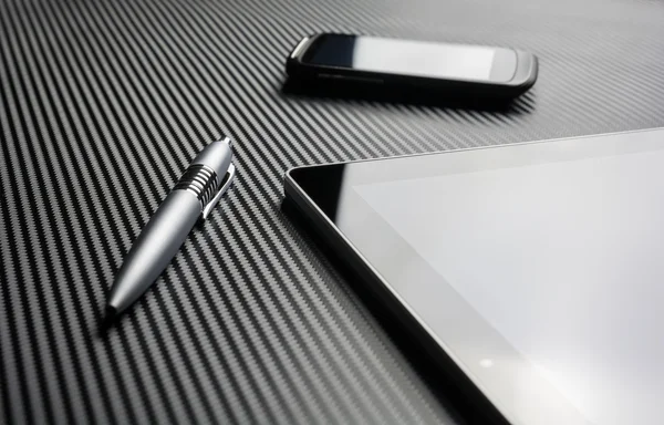 Blank Smartphone With Reflection And A Pen Lying Next To A Business Tablet On A Carbon Layer