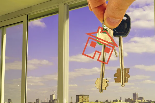 The keys to the apartment in hand against the window of a new home