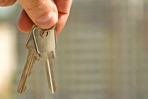 The keys to the apartment in hand on the background of houses