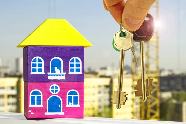 The keys to the apartment in the background of a house .