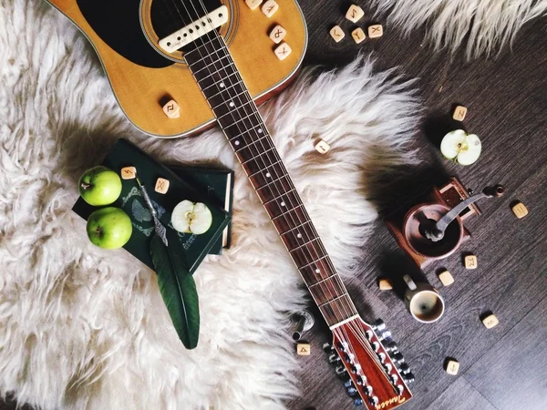 Acoustic guitar, vintage coffee mill, books and apples on fur mat