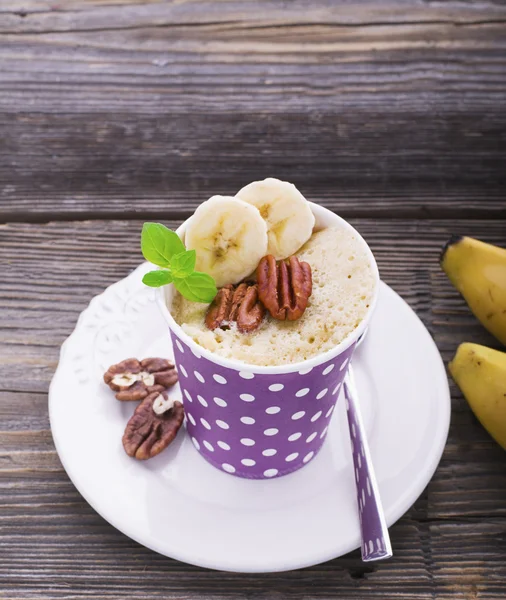 Quick breakfast in the microwave for five minutes. Homemade banana cup cakes in paper cups  portioned snack. two portions with pecan and  slices, fresh mint