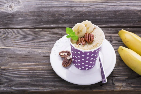 Quick breakfast in the microwave for five minutes. Homemade banana cup cakes in paper cups  portioned snack. two portions with pecan and  slices, fresh mint