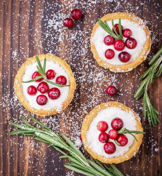 Tartlets of pastry with cream and fresh berries ripe cranberries, rosemary leaves