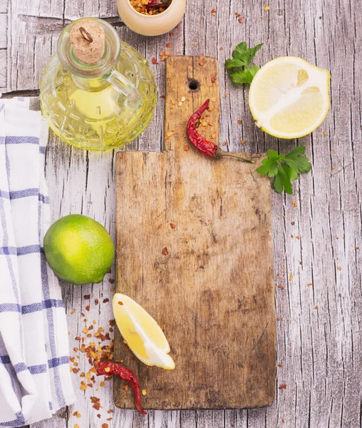 Old cutting board with a spicy red dried chilli, lemon and lime