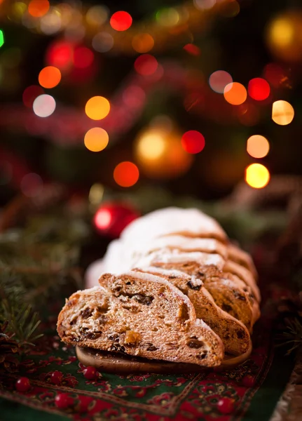 Traditional German Christmas cake Cranberry Stollen. Holiday xmas celebration decorations, ornaments, and candles.