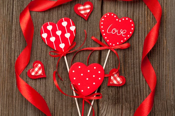 Variety of red hearts with ribbons on vintage wooden background