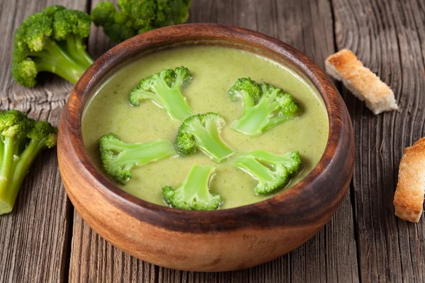Gourmet cream of broccoli green soup in wooden bowl with croutons