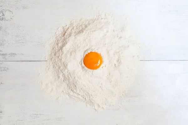 Dough ingredients on white table. Egg yolk and flour