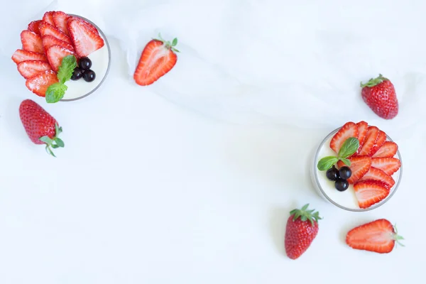 Summer sweet dessert food panna cotta in glass with empty frame for lorem ipsum design text and strawberries on white kitchen table background