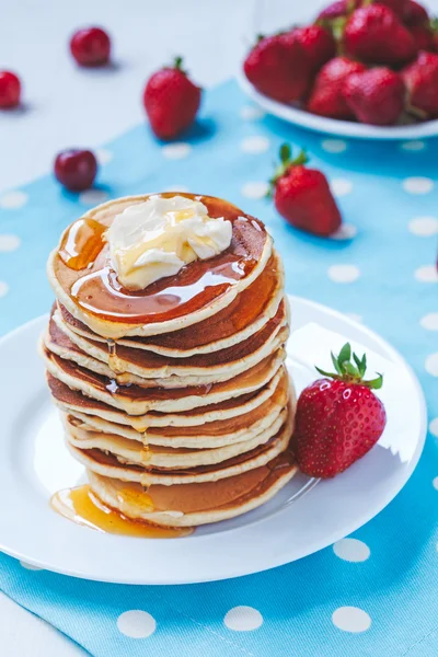 Pancakes traditional American homemade sweet dessert with honey, butter and strawberry on provence style background