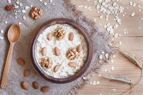 Healthy homemade oatmeal porridge with nuts. Perfect vegetarian diet breakfast concept. Vintage wooden table background.