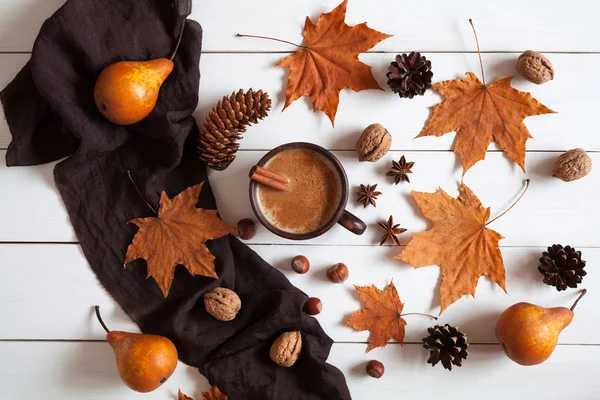 Autumn composition with hot cup coffee cinnamon, scarf, nuts and leaves. Concept of cozy morning, comfort, relax, melancholy, fall weather, home. Vintage white table background.