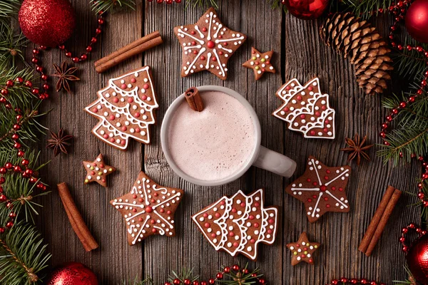 Cup of hot chocolate or cocoa with gingerbread cookies composition in new year decoration frame on vintage wooden table background. Homemade traditional recipe.