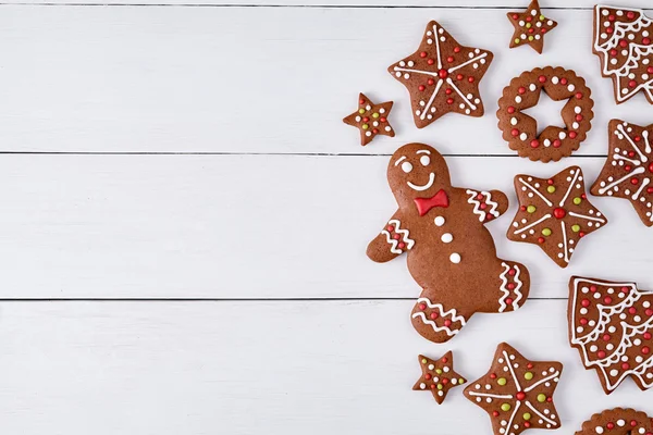 Gingerbread cookies christmas composition, with empty space for disign text on white wooden table background. New year traditional dessert food. Top view.