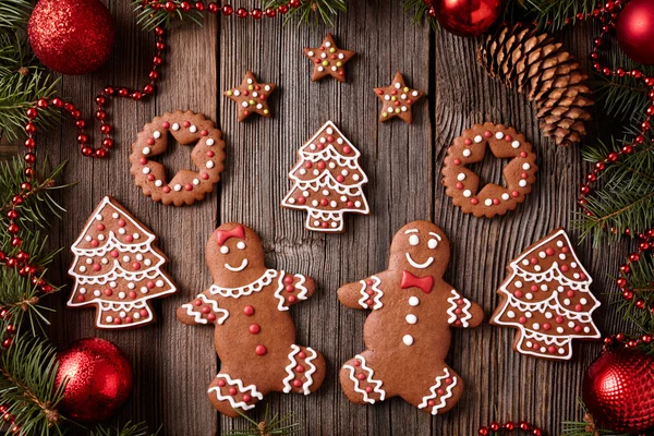 Gingerbread man and woman, fir, stars, christmas cookies composition with xmas tree decoration on vintage wooden table background. Homemade traditional new year dessert food recipe.