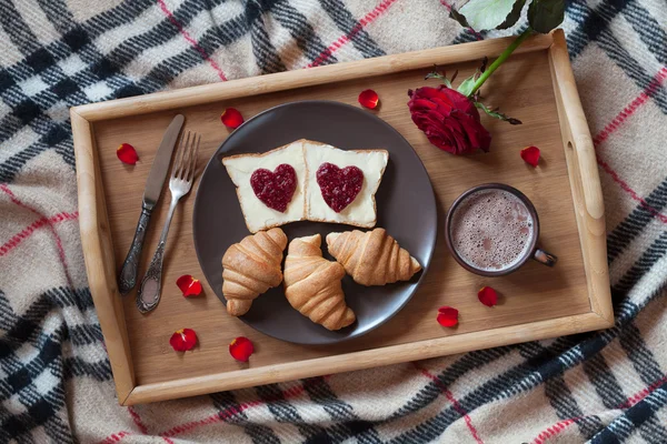 Valentines day breakfast in bed with rose flower and petals.