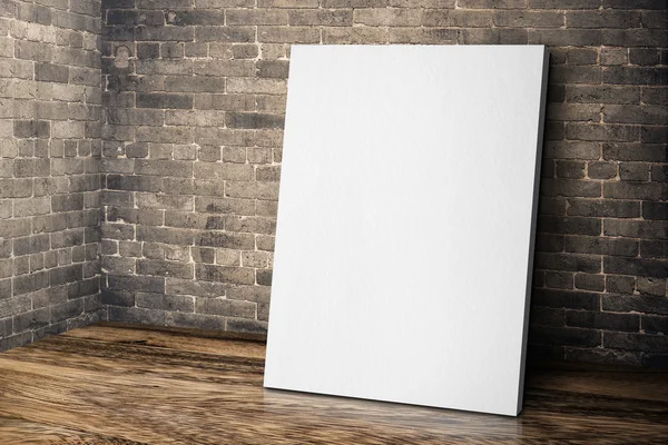 Blank white canvas frame leaning at grunge brick wall and wood f