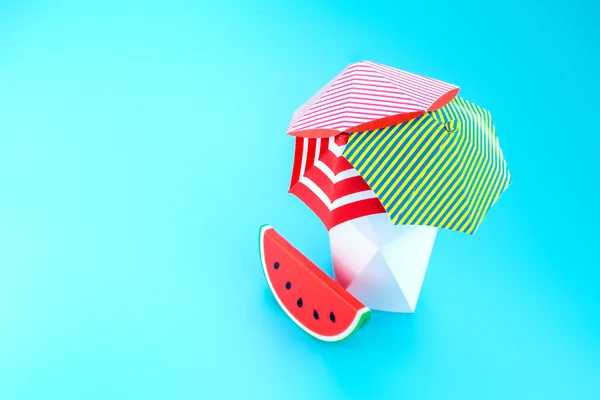 Beach umbrella with watermelon with polygon vase on blue backgro