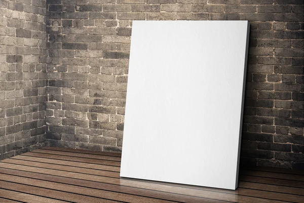 Blank white canvas frame leaning at grunge brick wall and wood