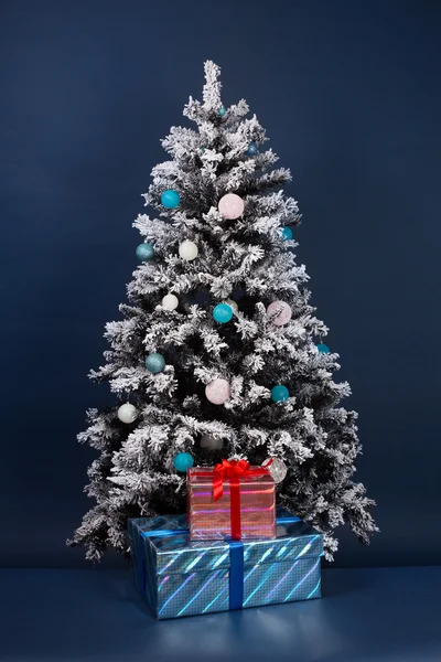 Two gift boxes near new year tree on dark blue background