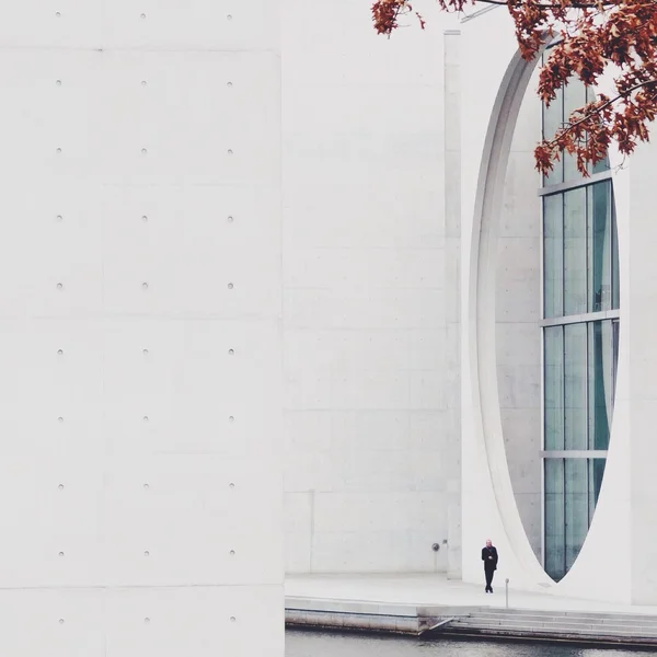 Singe man walking beside white wall with round window