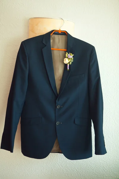 Suit jacket hanging on a hanger with  boutonniere in place