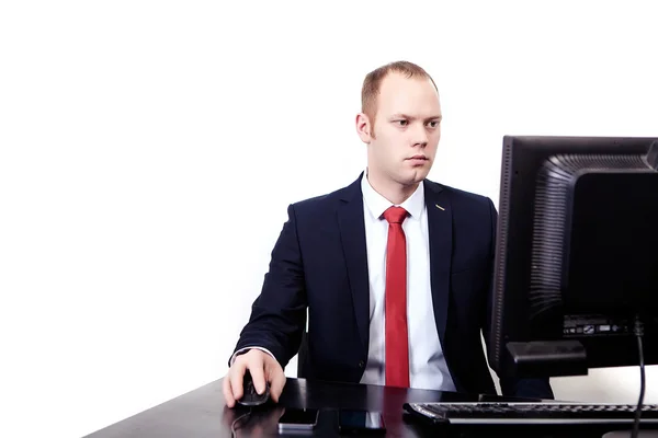 Businessman in  suit with a red tie sits on workplace computer.