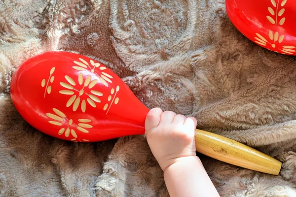 Baby hand with red wooden maracas