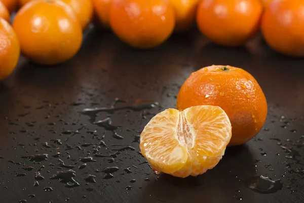 On the table with water drops lie tangerines