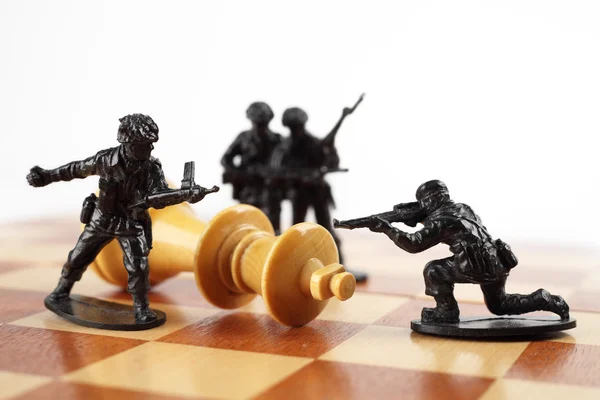 War concept. Toy soldiers kill chess King. Death of king.