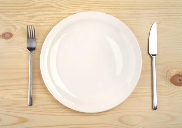 Empty plate with fork and knife on the wooden table