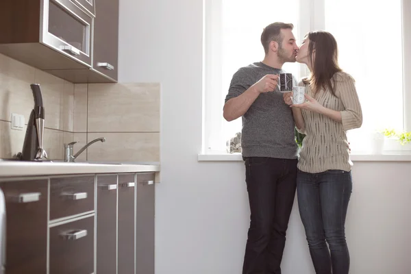 Young married people kissing in kitchen