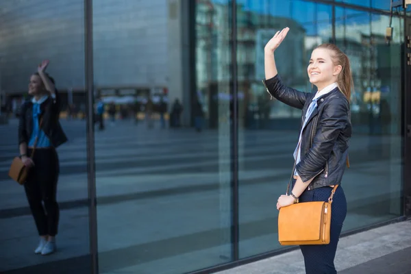 Woman meeting friends and waving hand in city center