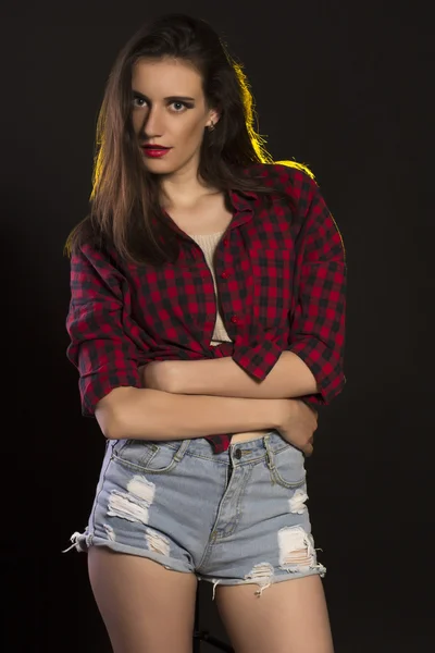 Pretty brunette woman in jeans shorts and plaid shirt