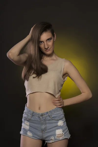 Attractive brunette woman in jeans shorts and crop top
