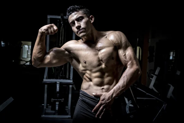 Young man exercising in dark and old gym