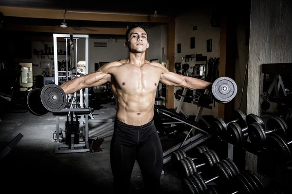 Young man exercising in dark and old gym