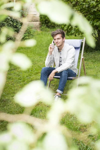 Focus on young man waiting on telephone in lush foliage