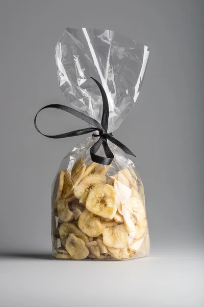 Luxury bag of dried banana chips isolated on grey background.