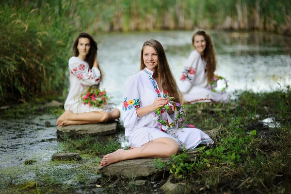 Three girls in the Ukrainian national clothes with wreaths of fl