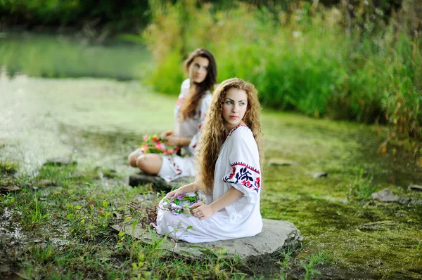 Two girls in the Ukrainian national clothes with wreaths of flow