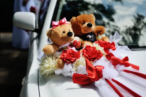 Two toy bear on the hood of wedding car. Toy bears dressed in Co