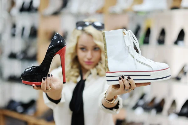 Beautiful girl chooses shoes. blonde girl measures the boots in the store